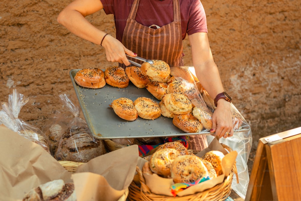 a woman in an apron is cutting pastries on a tray