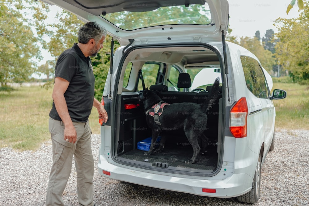 ein mann, der neben einem weißen lieferwagen mit einem schwarzen hund steht