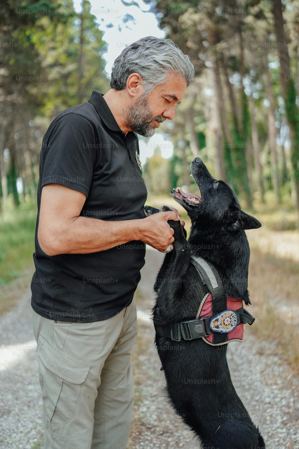 Un uomo in piedi accanto a un cane nero sulle zampe posteriori