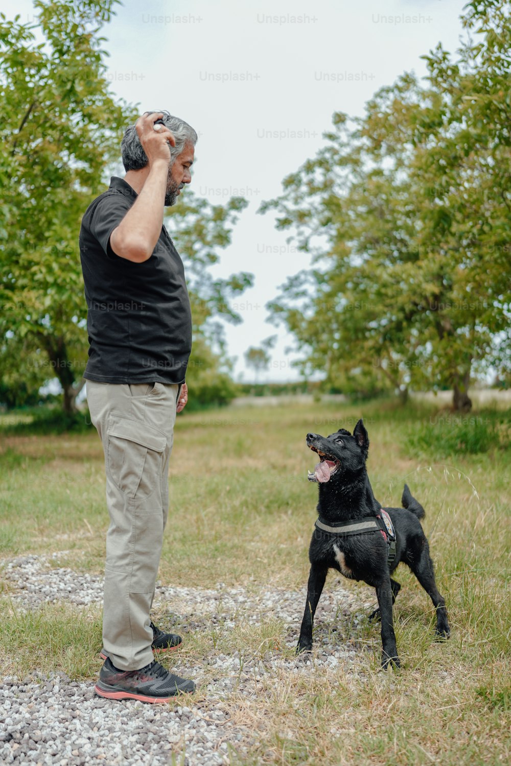 a man standing next to a black dog on top of a field