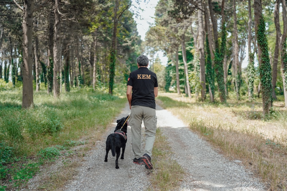 um homem passeando com um cachorro por uma estrada de terra