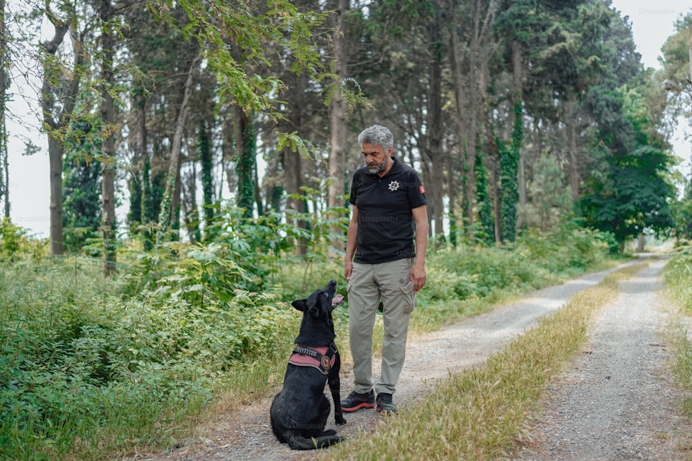 Un uomo in piedi accanto a un cane nero su una strada sterrata