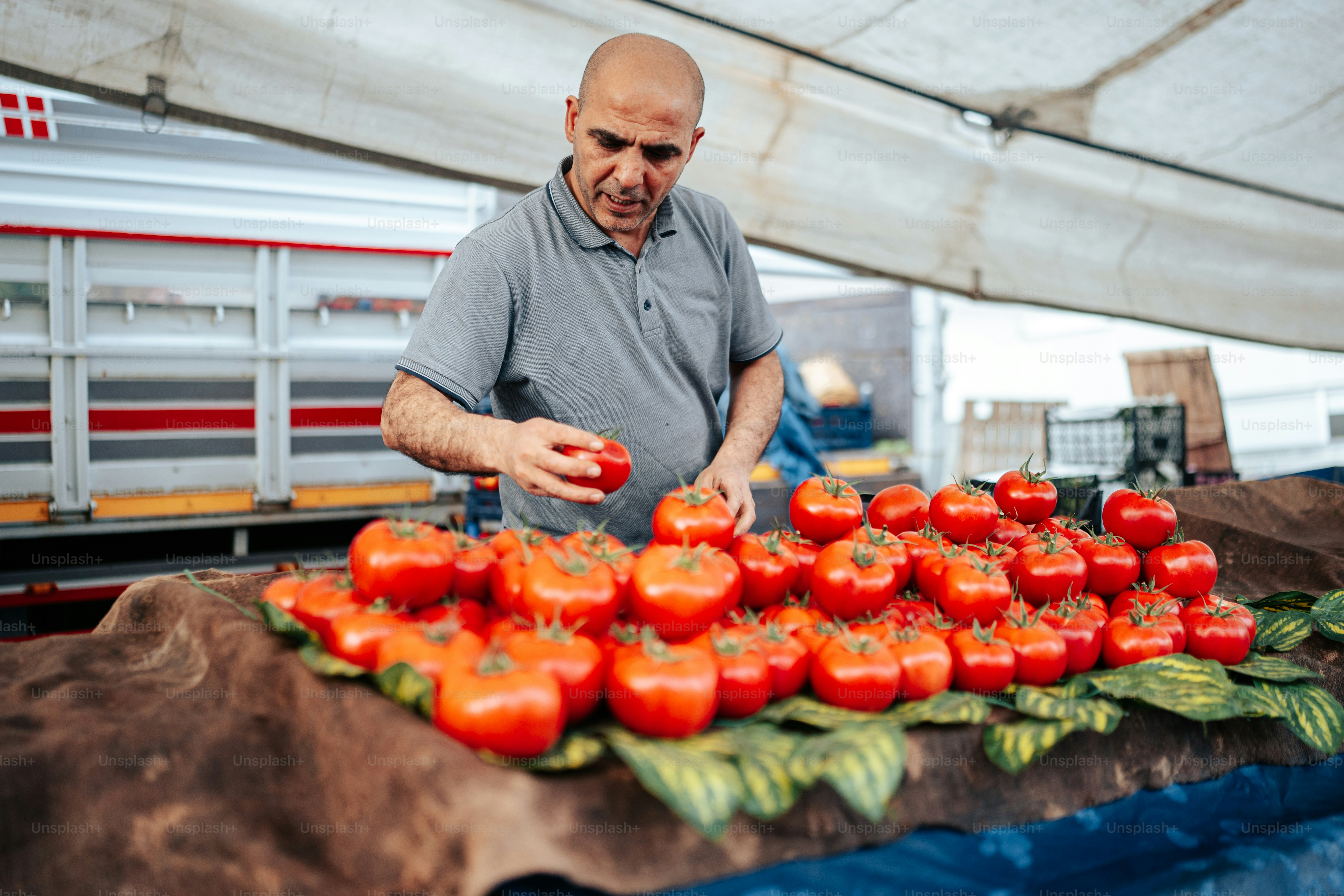 um homem parado em frente a uma pilha de tomates