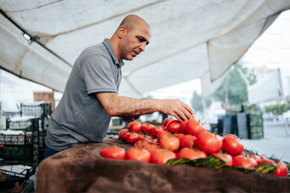 um homem em pé sobre uma mesa cheia de tomates