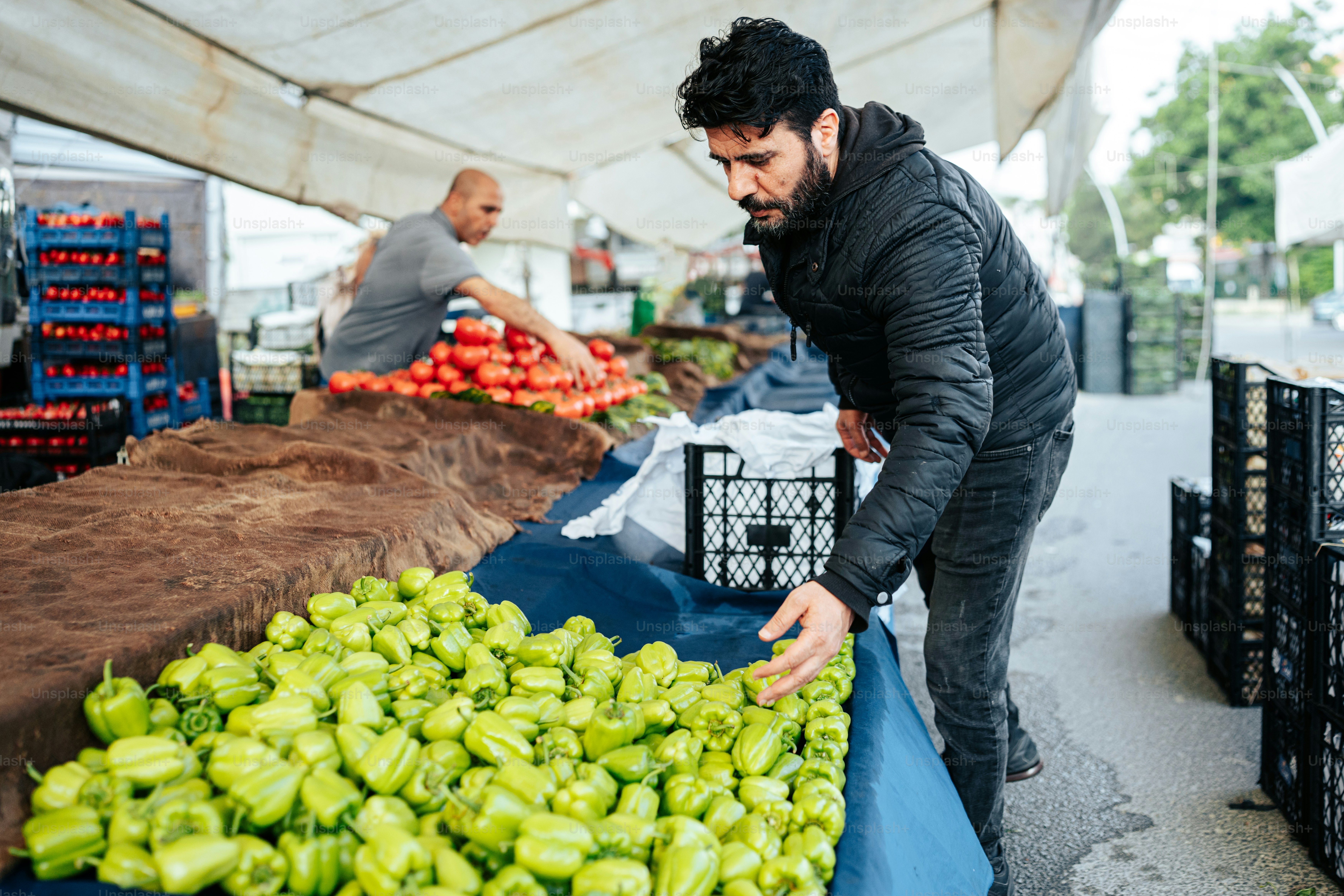 um homem ao lado de uma pilha de pimentões verdes