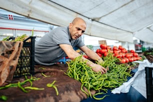 Ein Mann im grauen Hemd arbeitet auf einem Markt an Gemüse