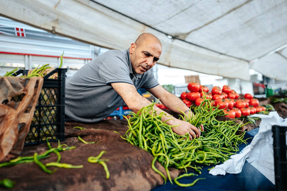 Un hombre con camisa gris trabajando en verduras en un mercado