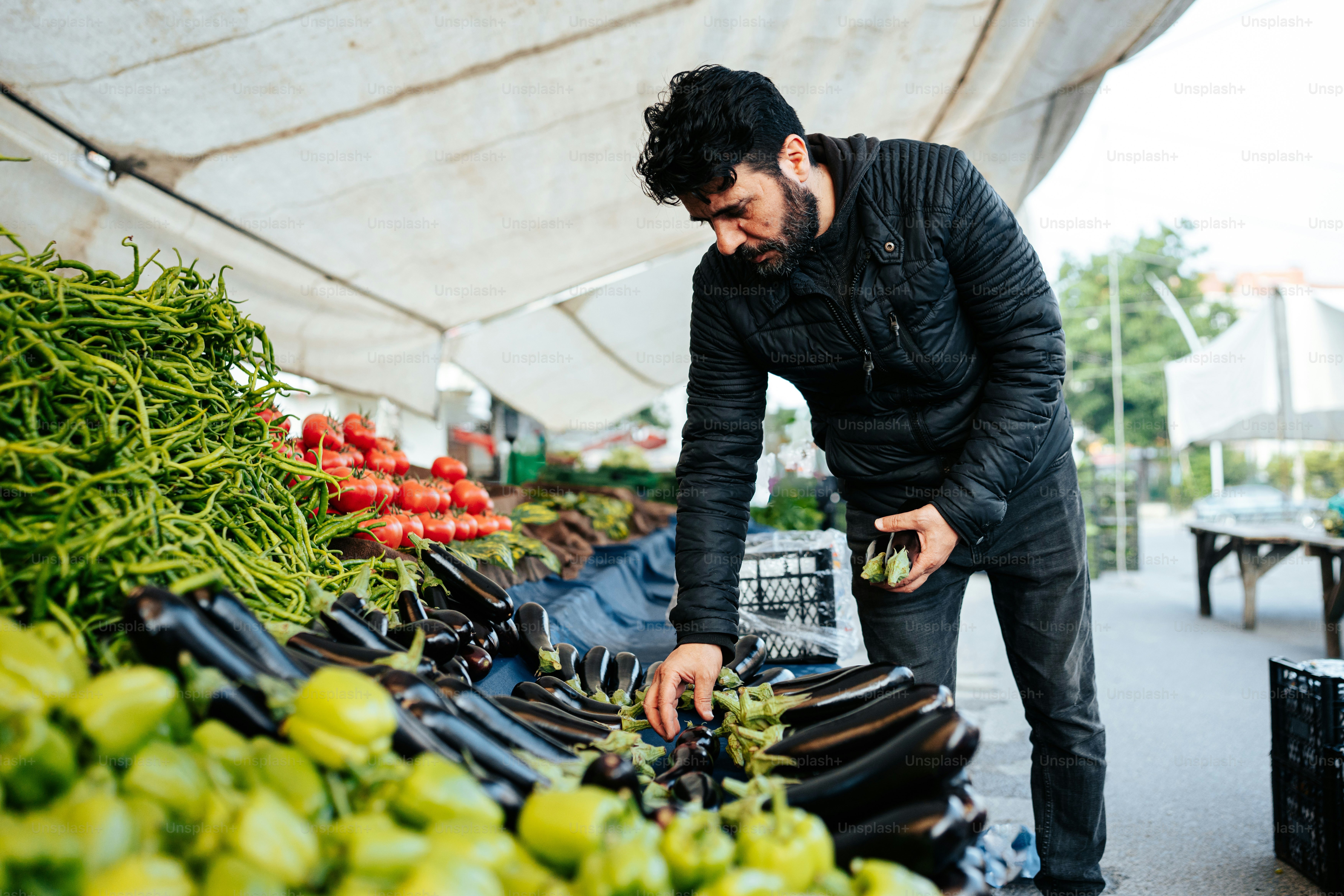 um homem em pé sobre uma pilha de frutas e legumes