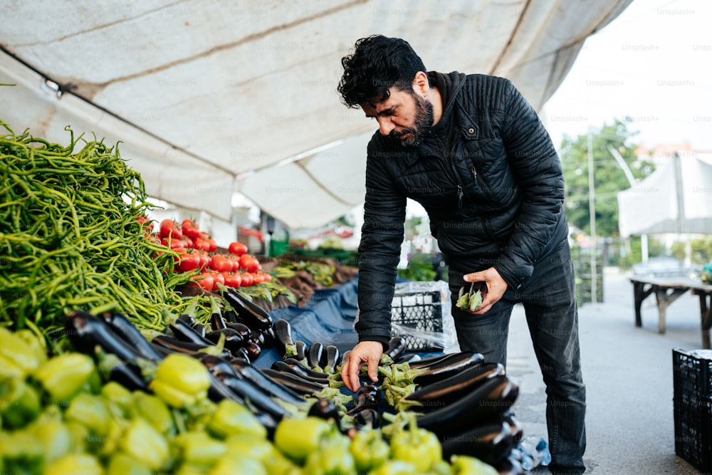 Un uomo in piedi sopra un mucchio di frutta e verdura