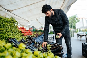 a man standing over a pile of fruit and vegetables