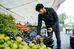 um homem em pé sobre uma pilha de frutas e legumes