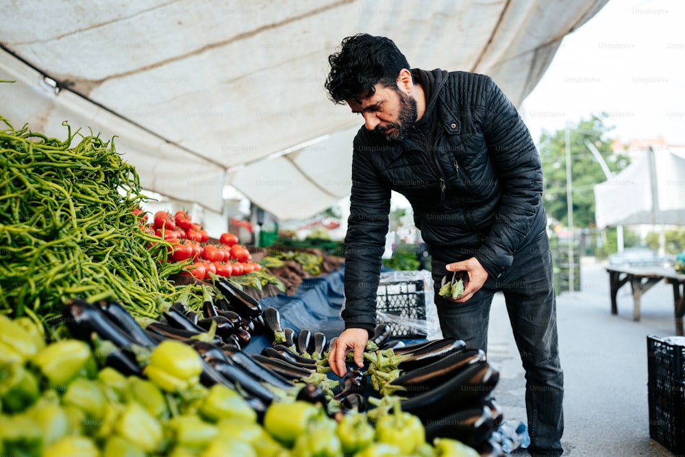 Un hombre parado sobre un montón de frutas y verduras