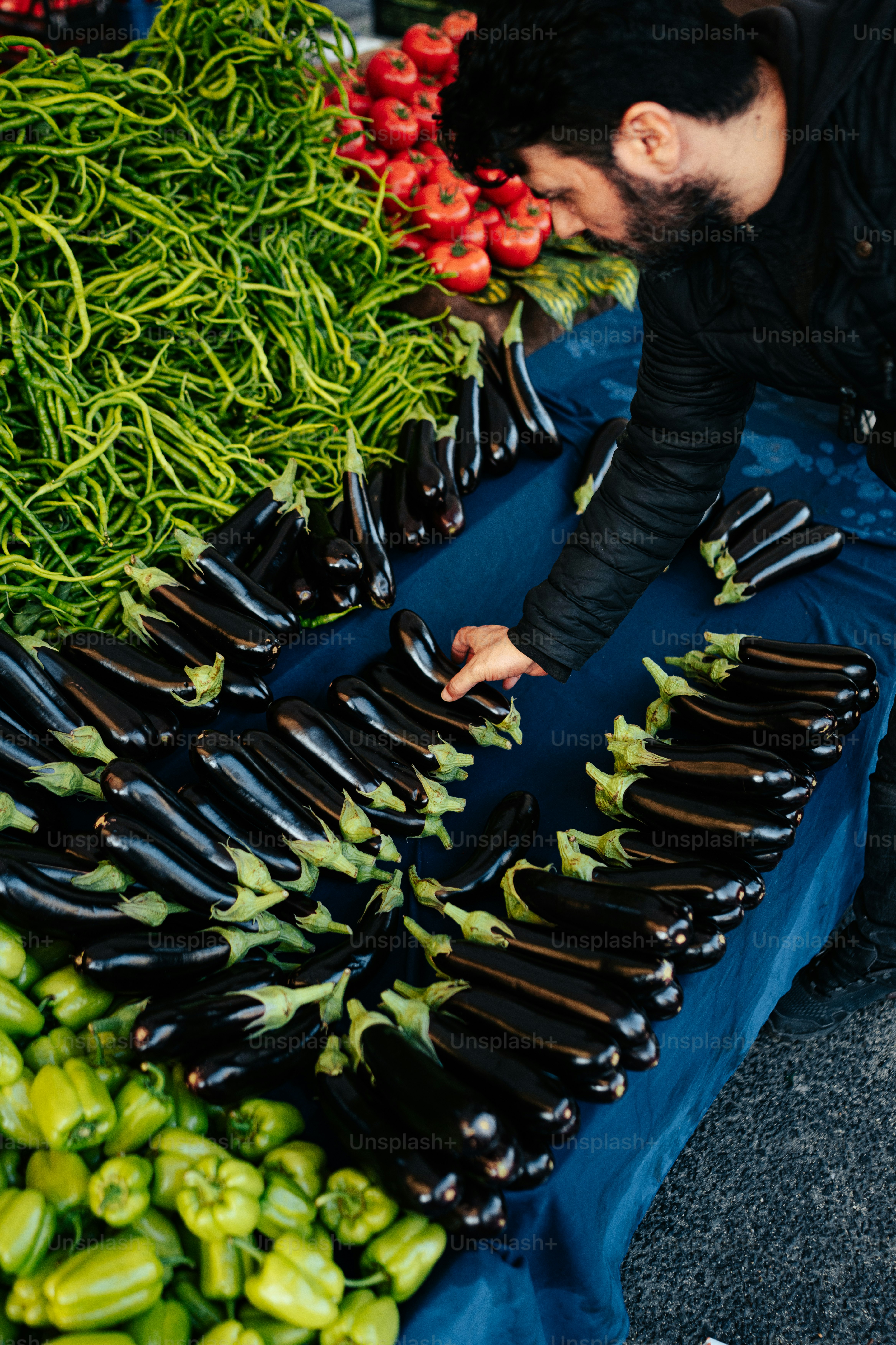 um homem ajoelhado ao lado de uma mesa cheia de legumes