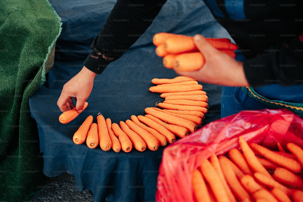 une personne tenant un bouquet de carottes sur une table