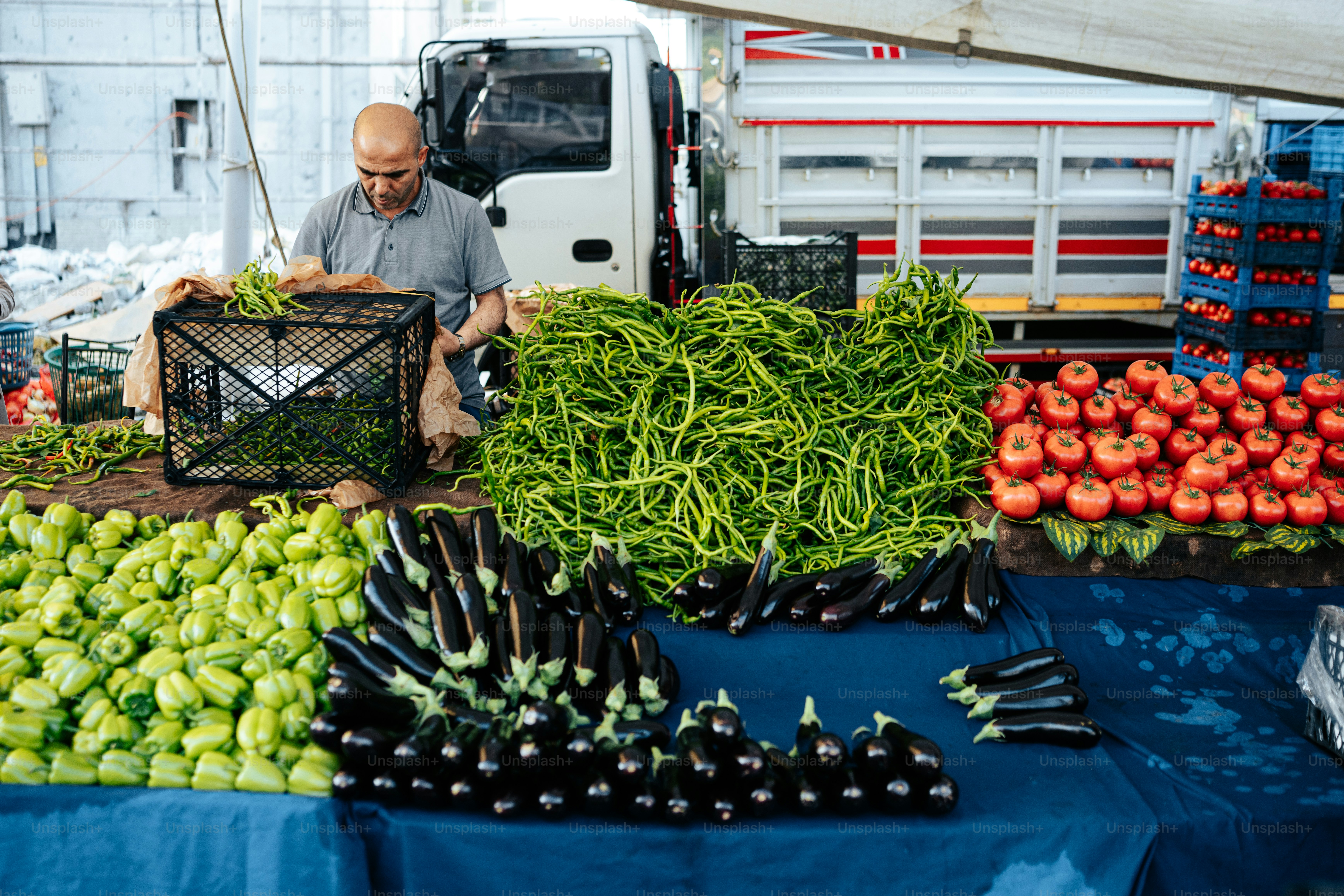 um homem parado em frente a uma mesa cheia de legumes