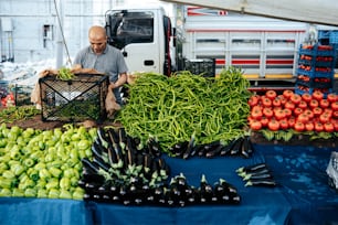 Un hombre parado frente a una mesa llena de verduras