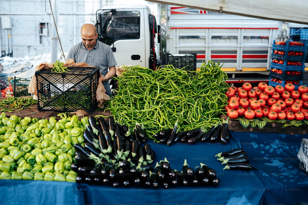 um homem parado em frente a uma mesa cheia de legumes