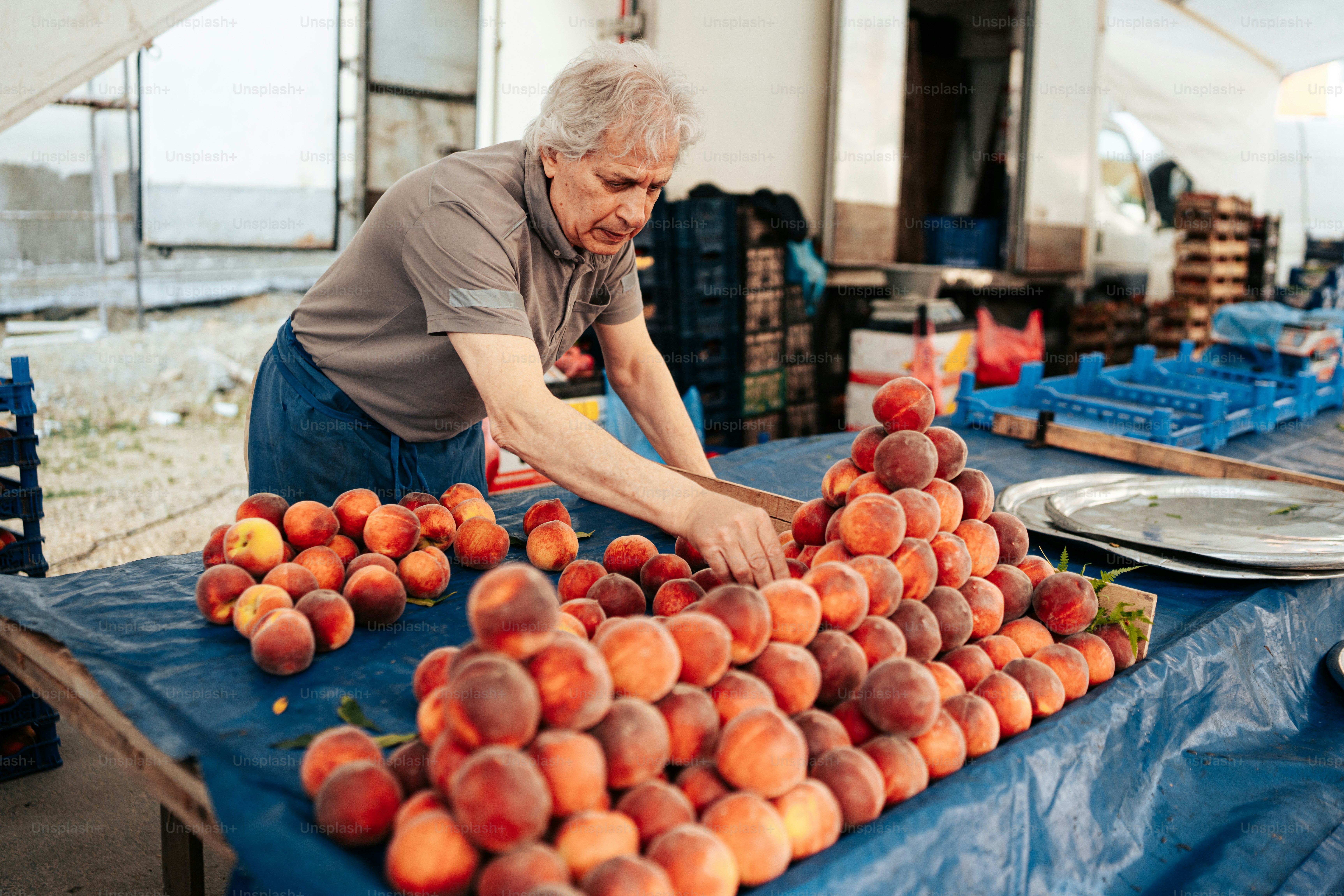 an older woman is arranging peaches on a table