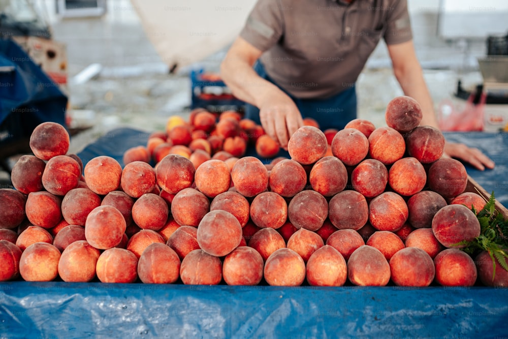 a man standing next to a pile of peaches
