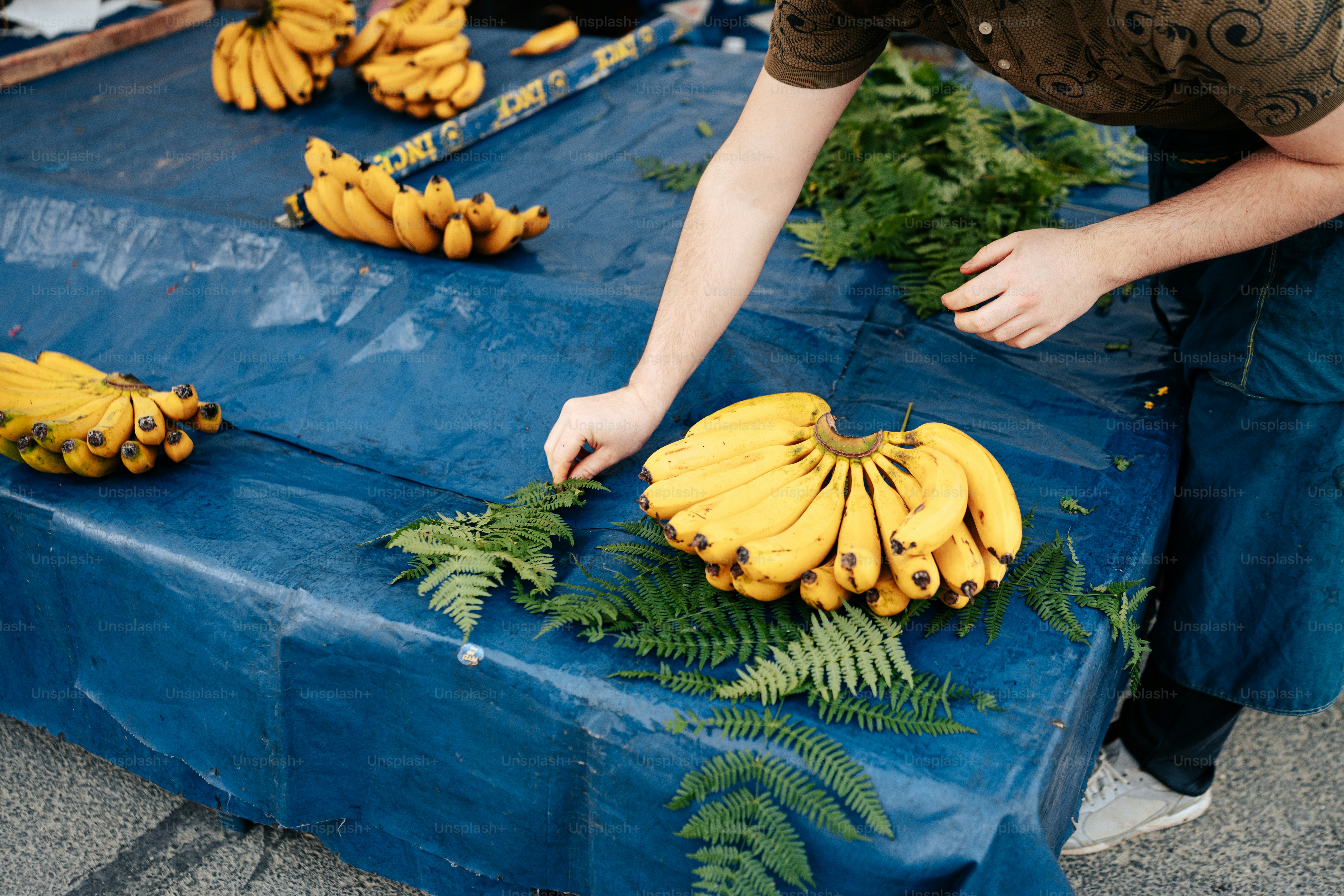 a man reaching for a bunch of bananas on a table
