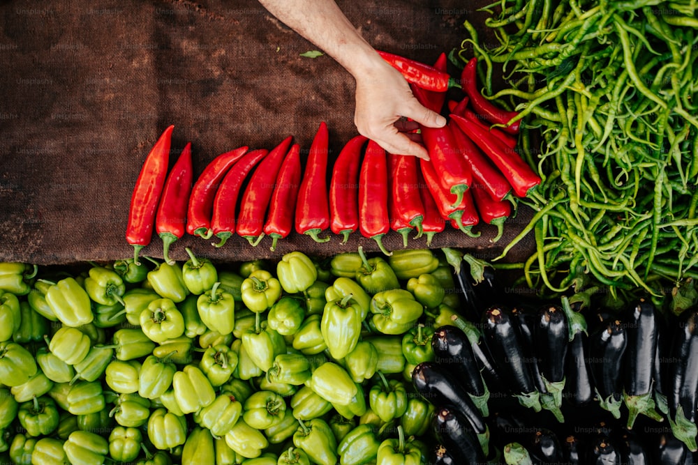 a person reaching for peppers at a vegetable stand