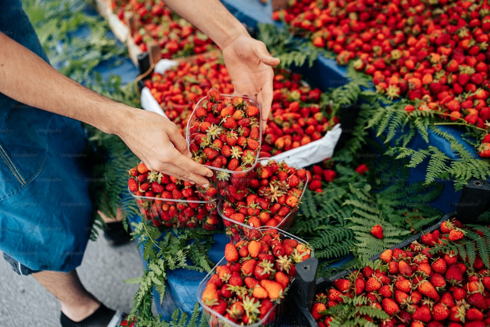 a person picking strawberries from baskets at a market