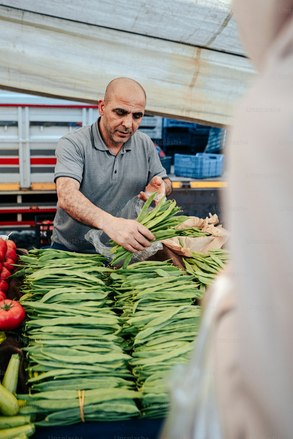 Un homme debout devant une table remplie de légumes