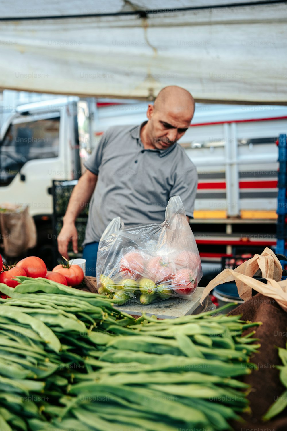 a man standing next to a pile of vegetables