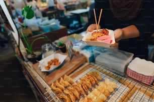 a person holding a tray of food on a table