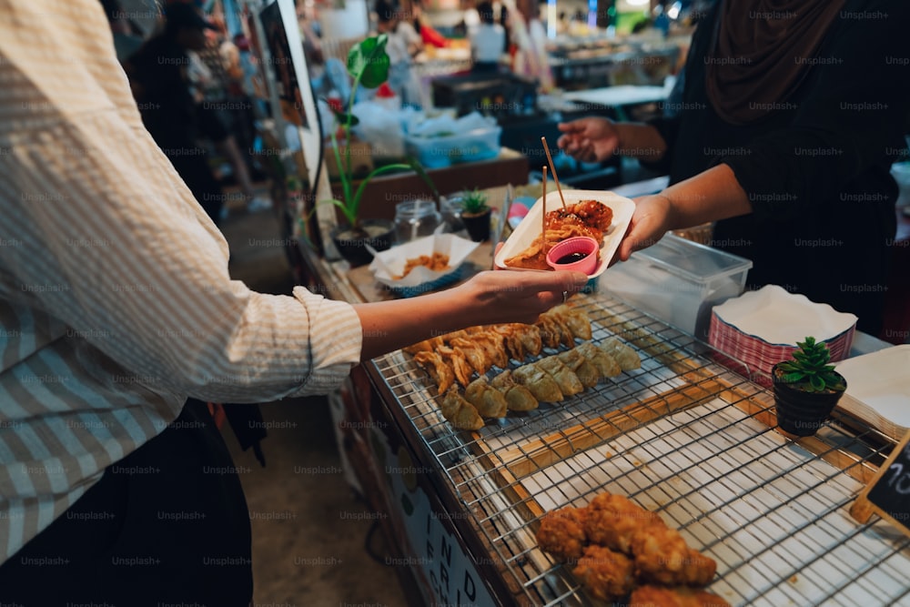 a person serving food to another person at a food stand