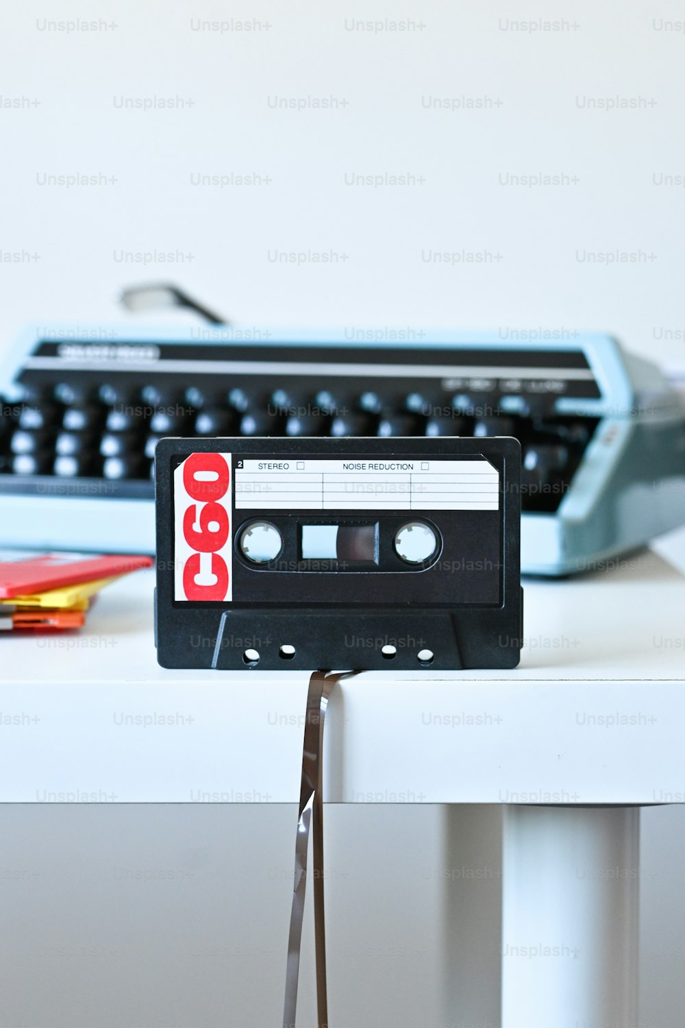Un lettore di cassette vecchio stile seduto su un tavolo accanto a una macchina da scrivere