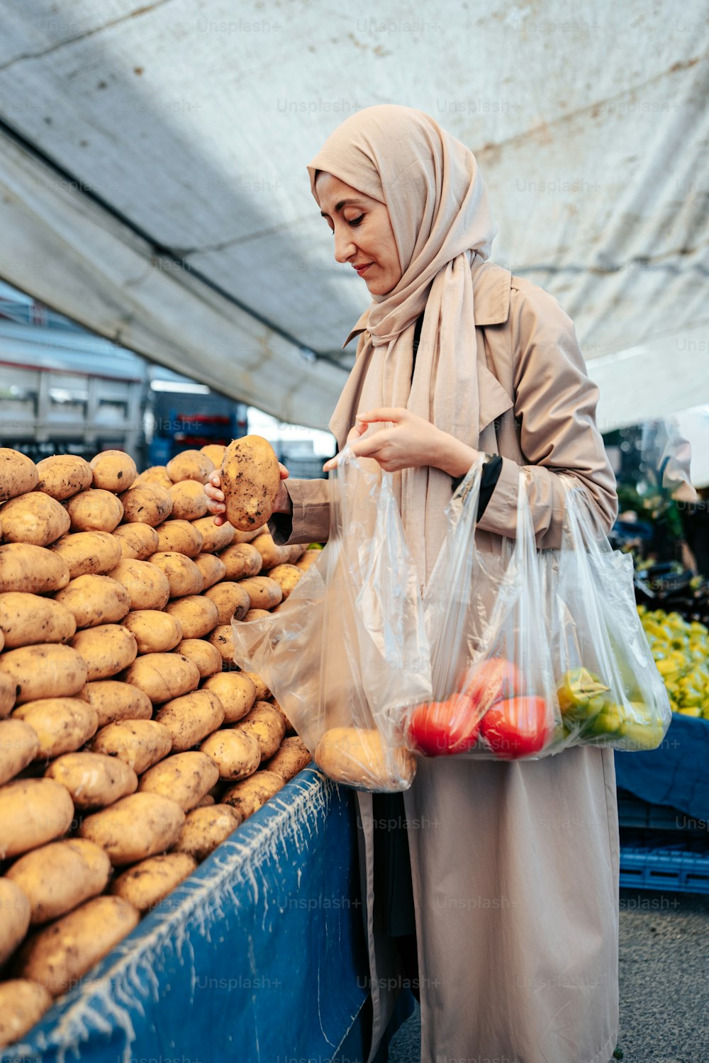 a woman in a hijab holding a bag of potatoes