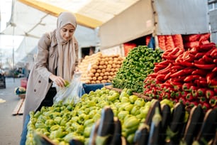 uma mulher em pé em frente a uma exposição de frutas e legumes