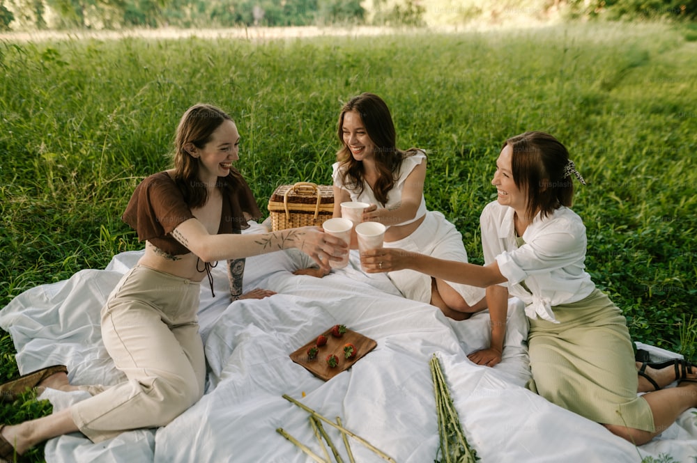 a group of women sitting on top of a lush green field