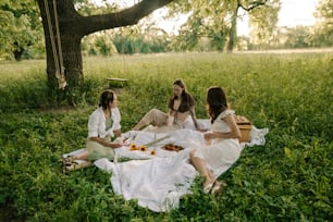 a group of women sitting on top of a lush green field