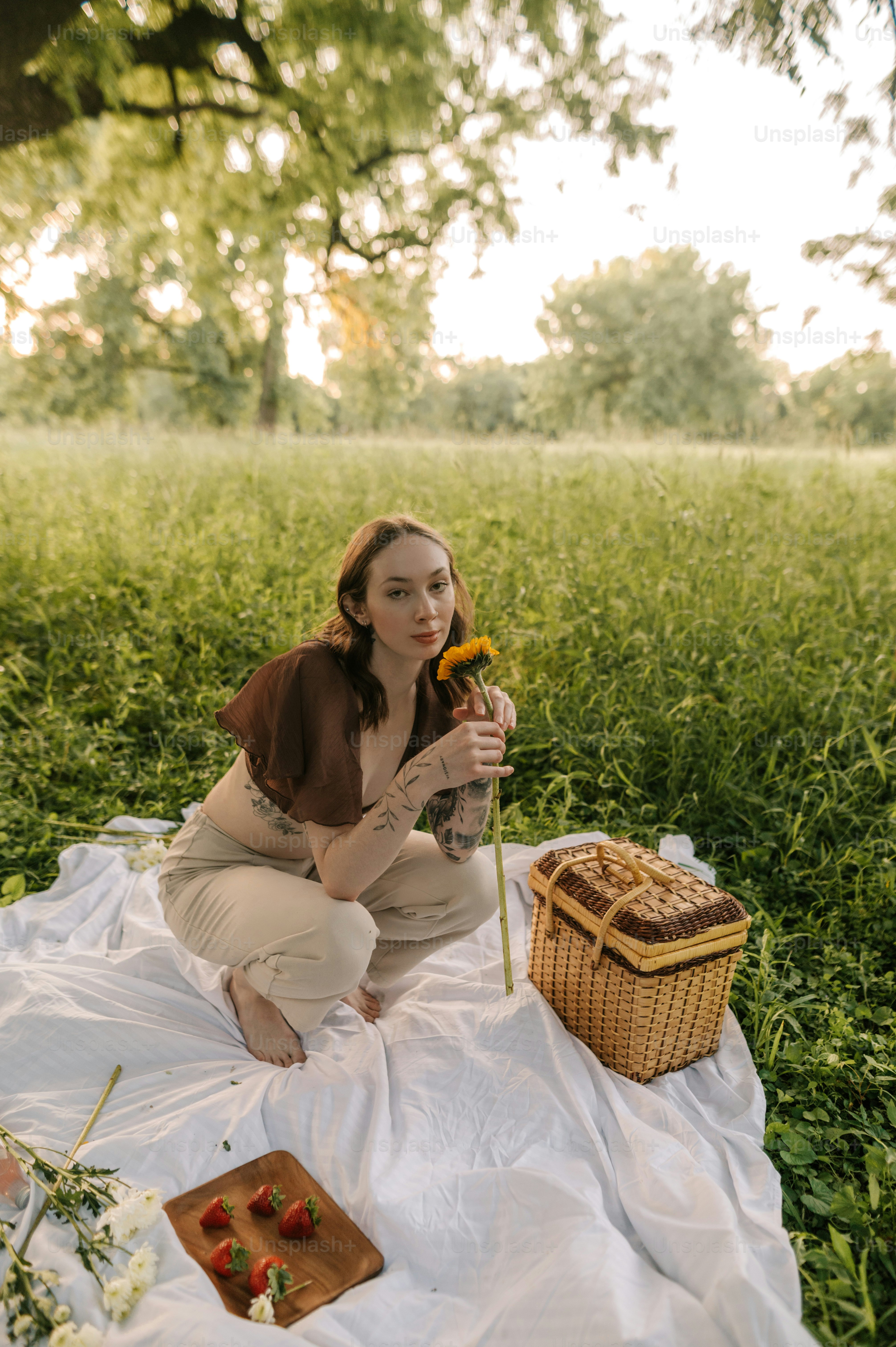 eine frau, die auf einer decke sitzt und eine blume hält