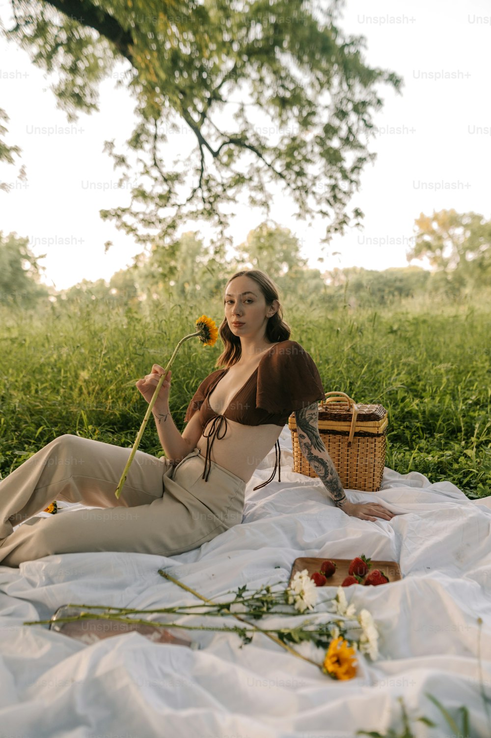 a woman sitting on a blanket holding a flower