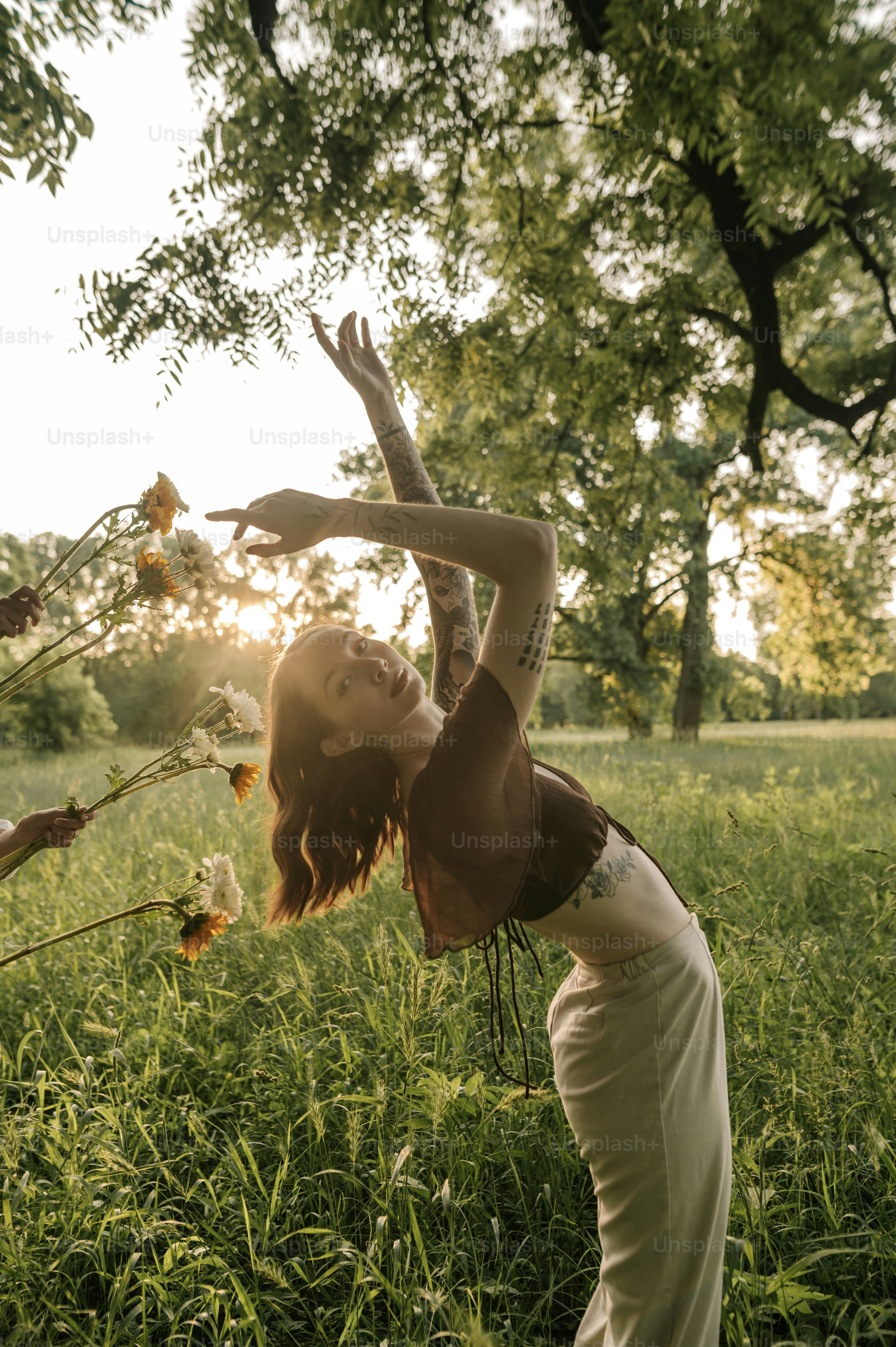 eine frau auf einem feld, die nach einer blume greift
