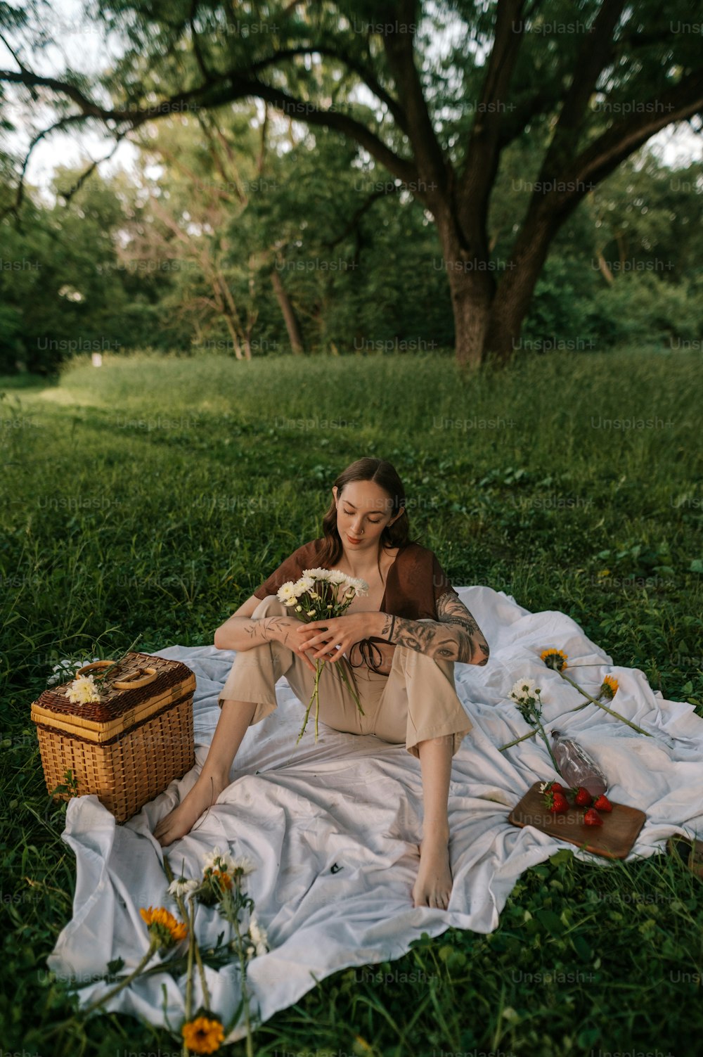 Una mujer sentada sobre una manta en la hierba