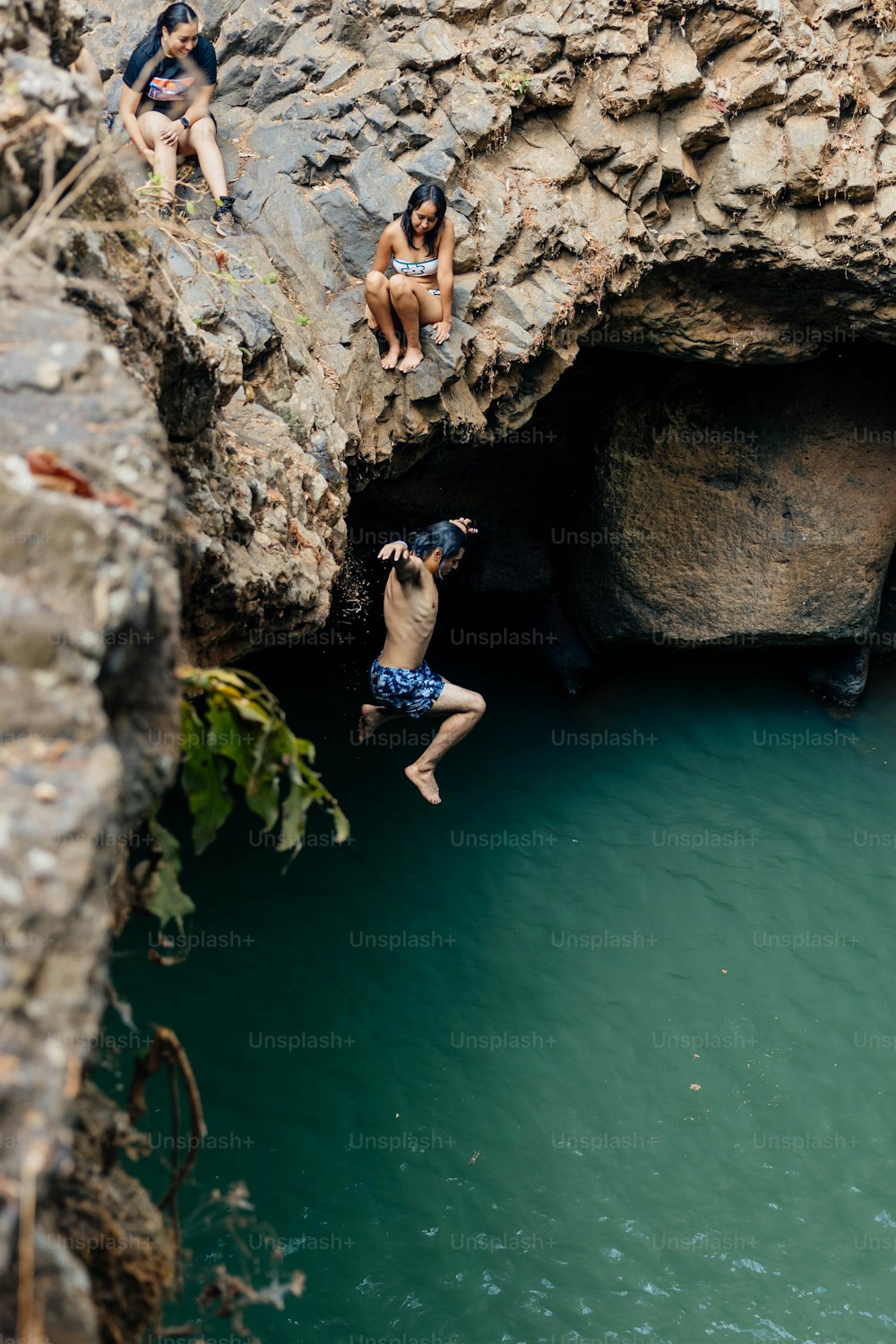 a group of people jumping off a cliff into a body of water