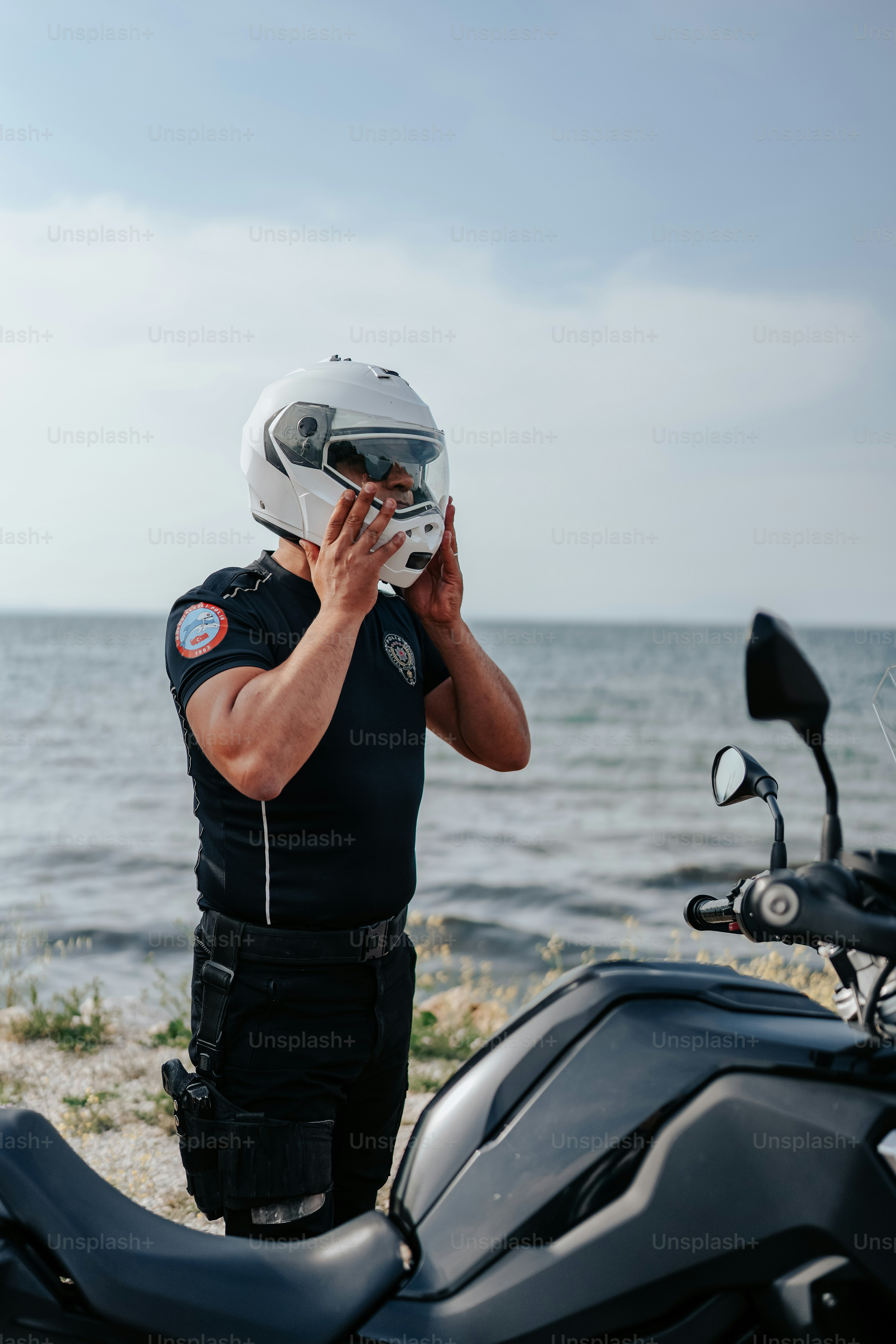 海の近くのバイクの隣に立っている男