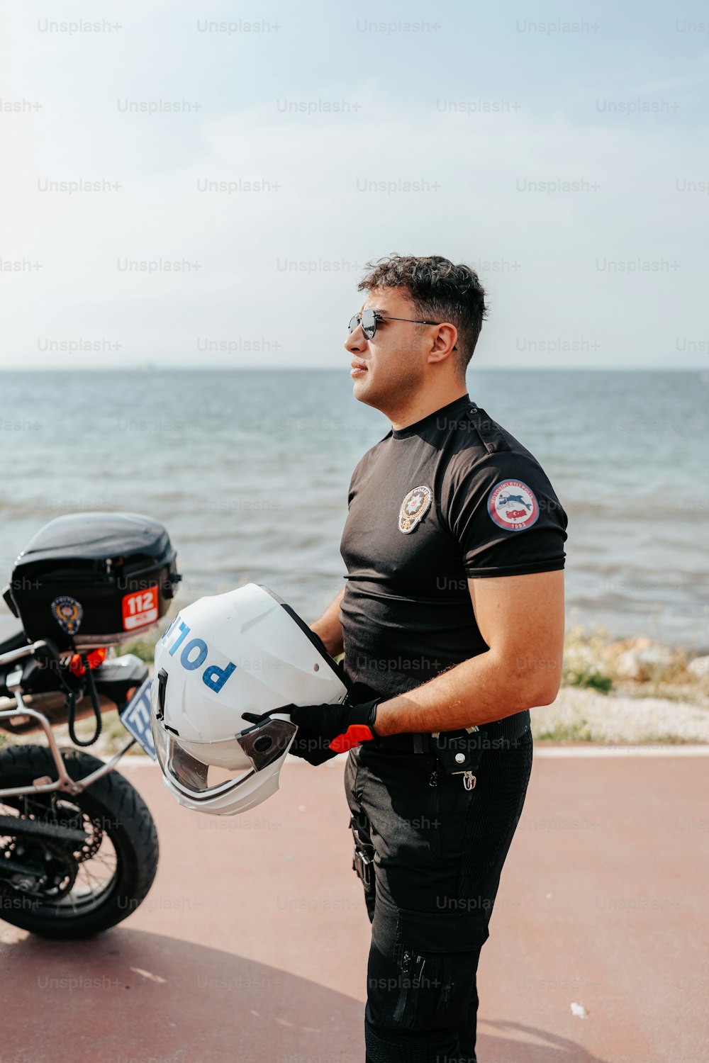 Un hombre parado junto a una motocicleta cerca del océano