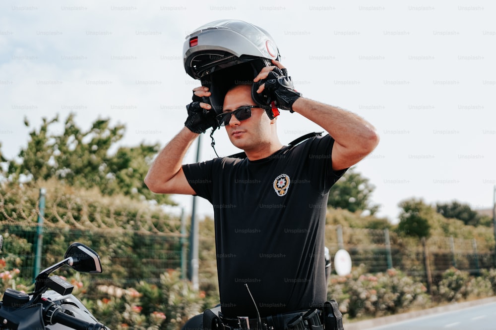 a man in a black shirt is holding a helmet on his head