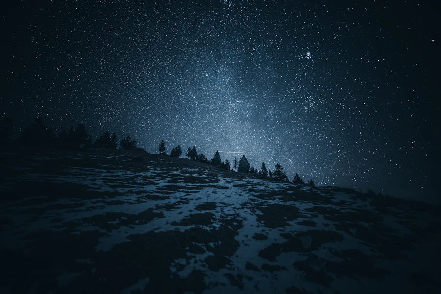 Dark, star-filled night sky over a landscape