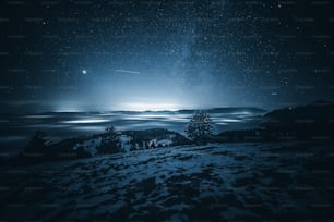 a night sky with stars and clouds over a mountain
