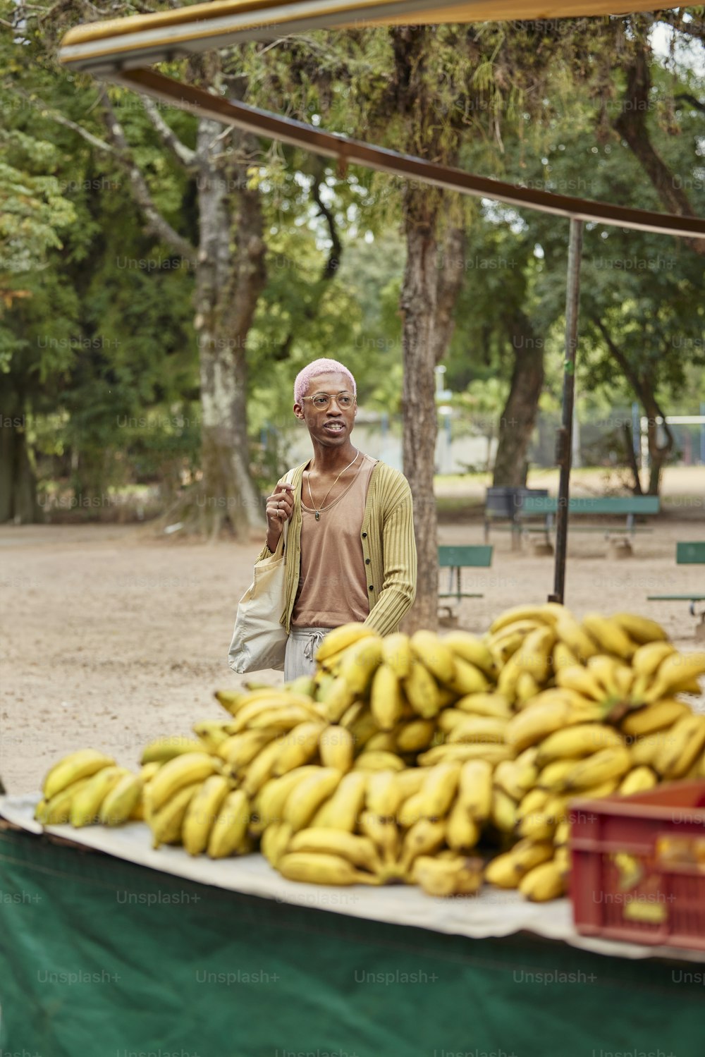 Un hombre de pie junto a un montón de plátanos
