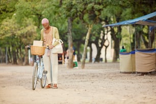 um homem parado ao lado de uma bicicleta em uma estrada de terra