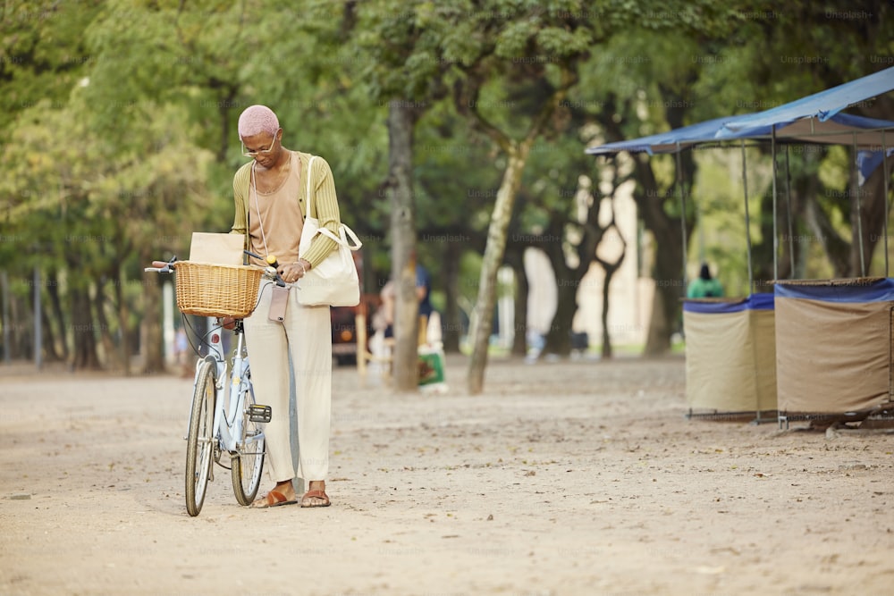 Un hombre parado junto a una bicicleta en un camino de tierra