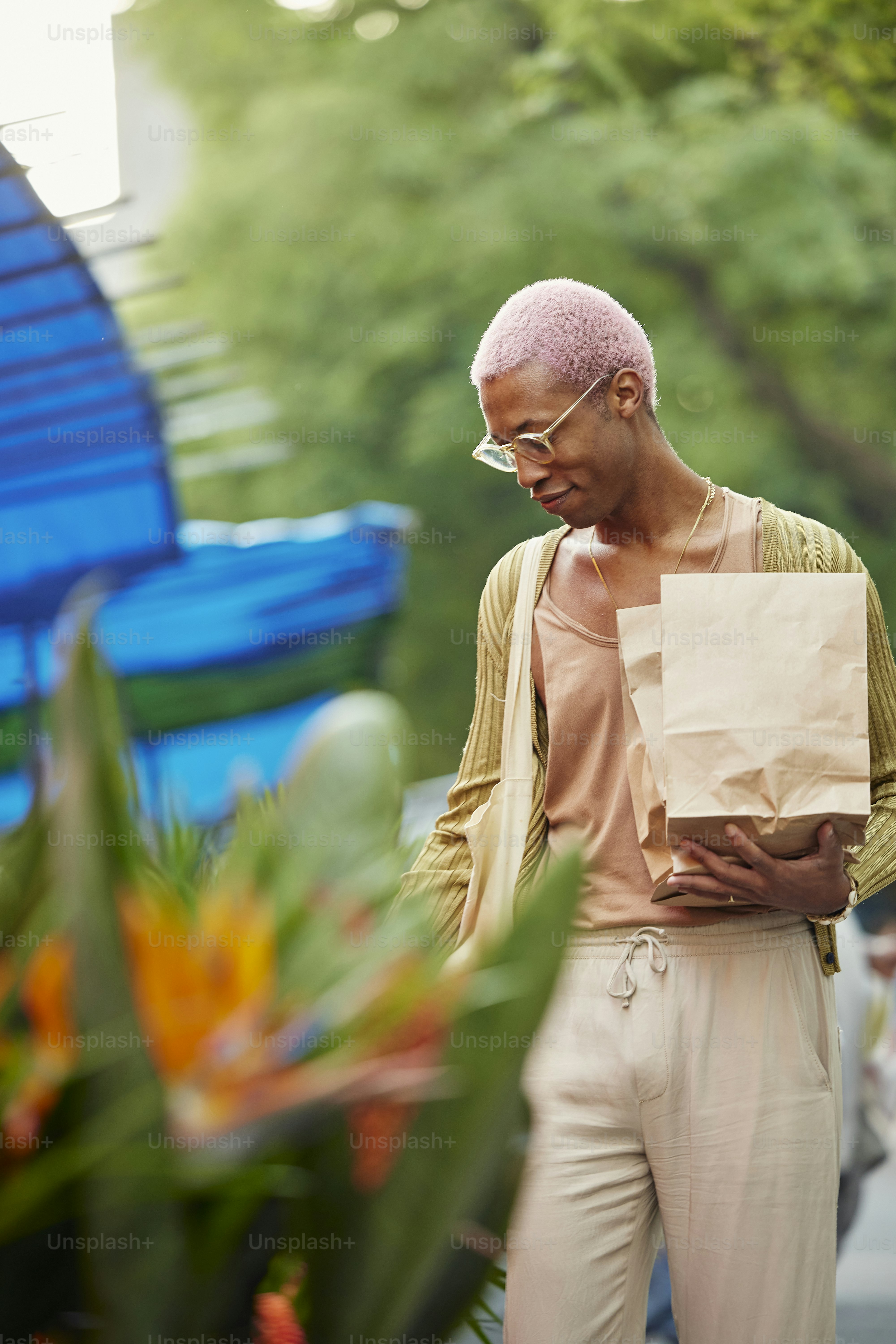 a man with pink hair and glasses holding a paper bag