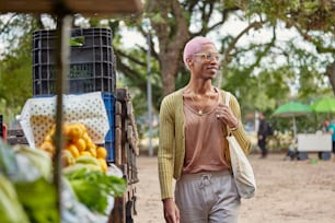 um homem com um moicano rosa passando por uma banca de frutas